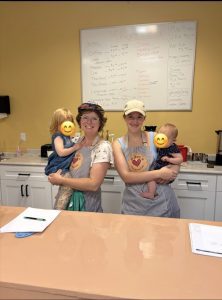 The women who own Mikey's Play Cafe hold their children in front of a snack bar